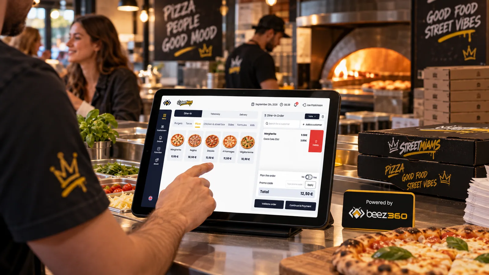 Prise de commande sur BeezPOS devant le four d’une pizzeria, avec un panneau Beez360 au comptoir.